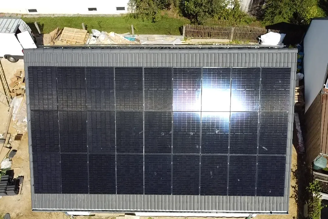 Drohnenaufnahme: großflächige Photovoltaikanlage auf einem Satteldach, Module reflektieren die Sonne