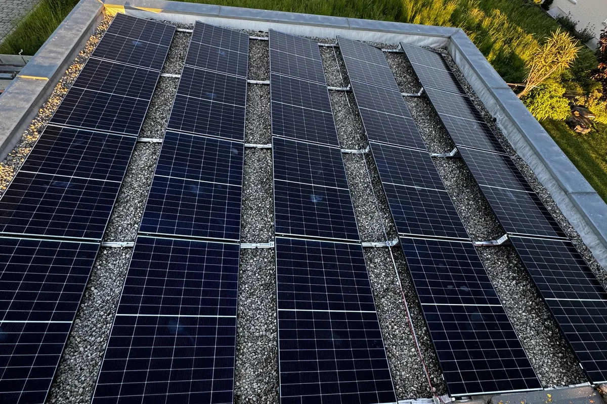 Aufgeständerte Photovoltaik-Module auf einem Kiesdach in der Abendsonne