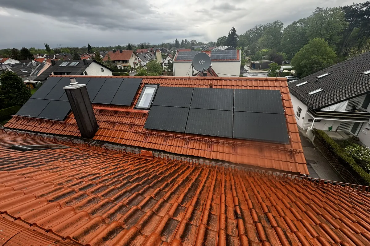 Photovoltaik-Module beidseits des Kamins auf einem Ziegeldach, Blick über die Nachbarschaft